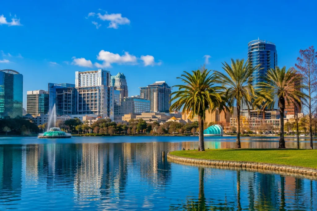 Downtown Orlando, FL skyline across a lake with palm trees