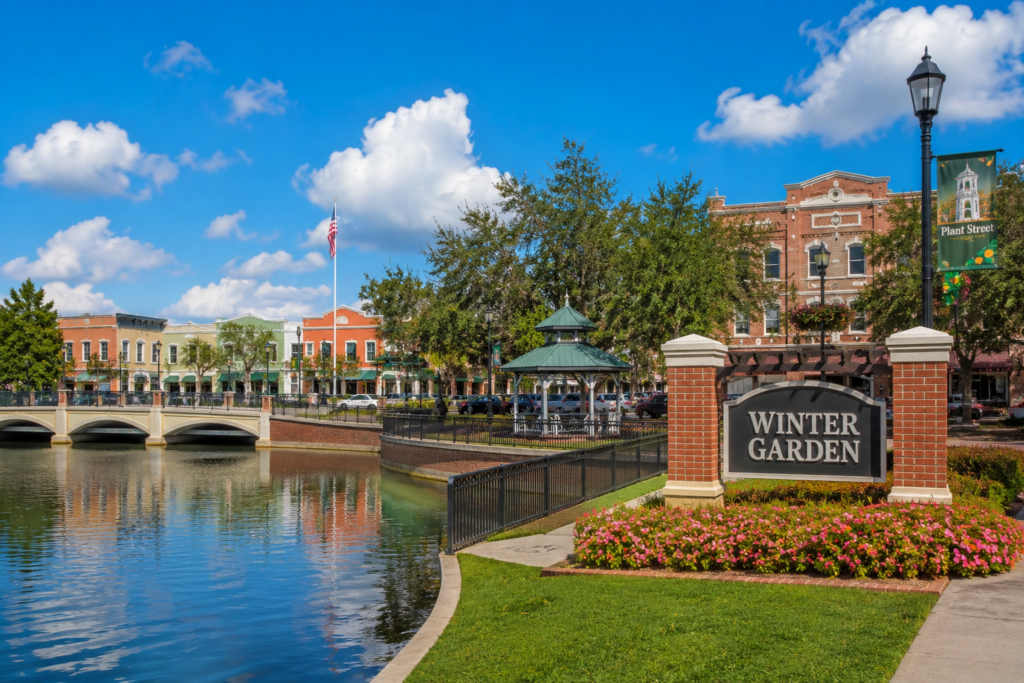 Winter Garden, FL sign beside a lake with a gazebo and downtown buildings
