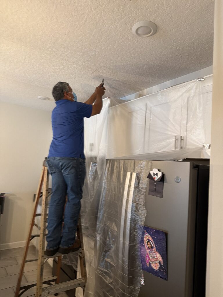 Plumber on a ladder repairing a ceiling leak