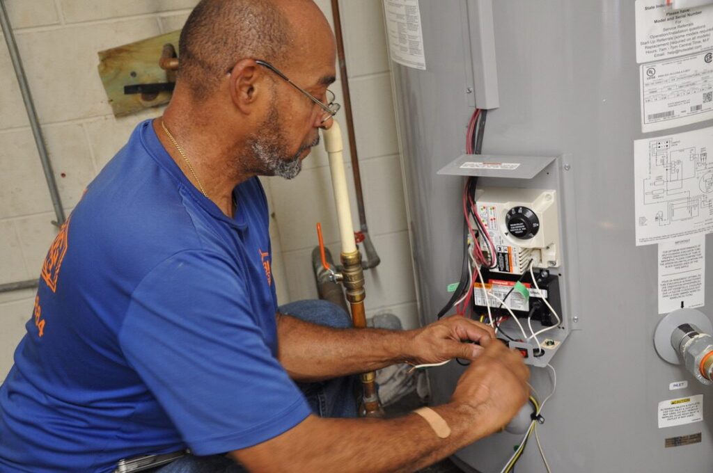 Plumber servicing a wall-mounted tankless water heater