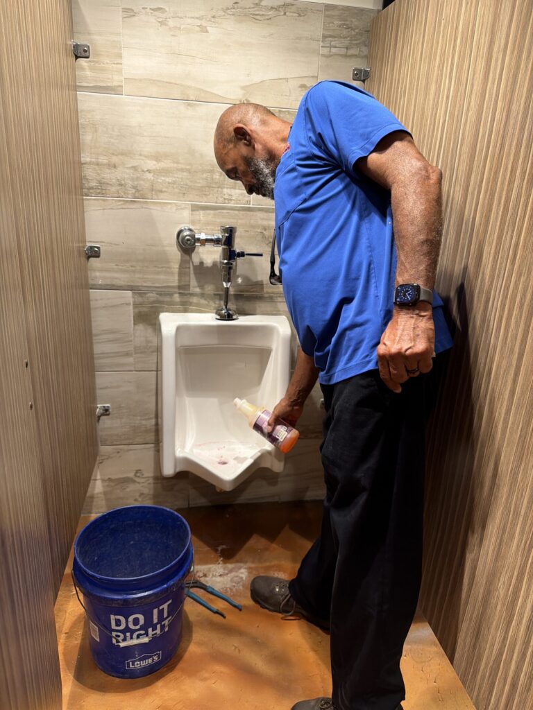 Plumber servicing a commercial restroom urinal