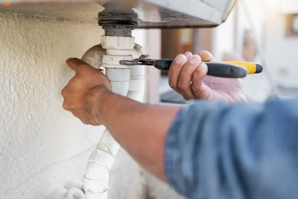 Plumber tightening a sink drain pipe with a wrench
