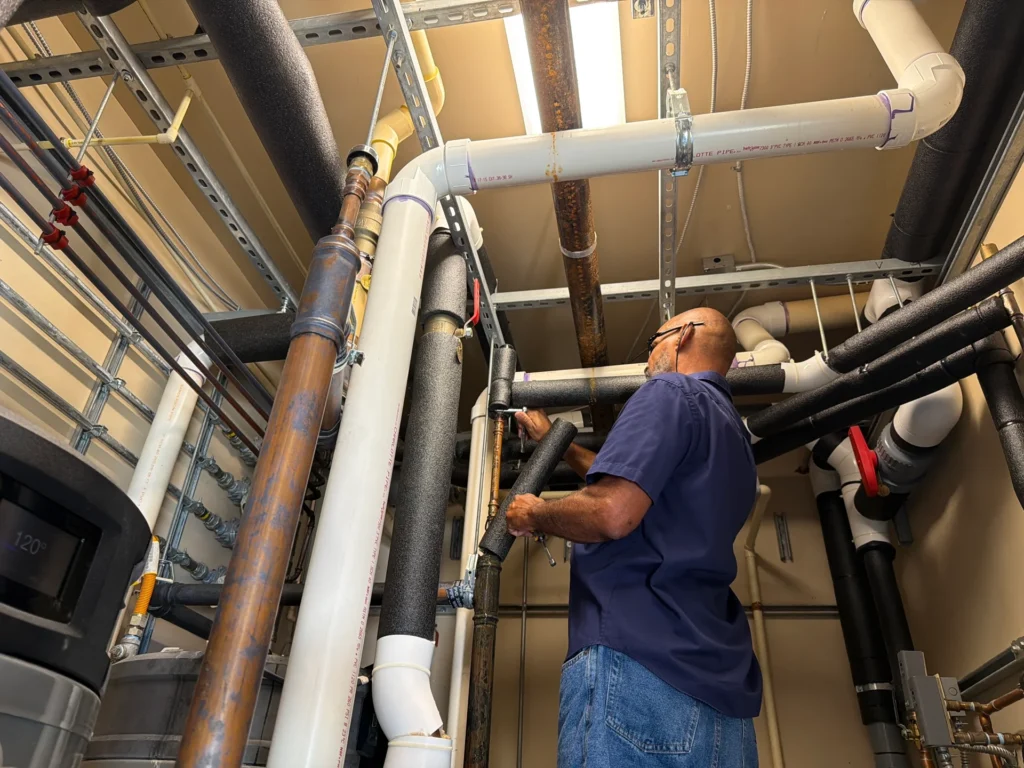 Plumber inspecting overhead pipes in a utility room