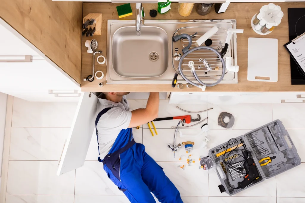 Overhead view of a plumber working under a kitchen sink